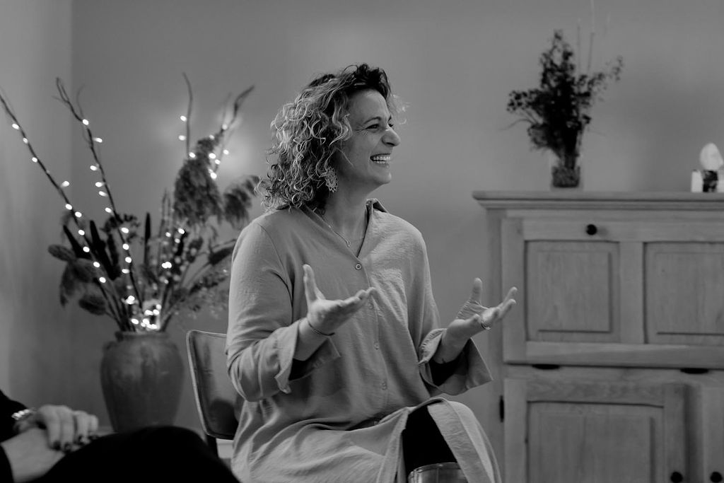 Tiziana lacht met open handen tijdens een bijeenkomst